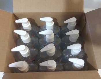 A top view of an opened box filled with 12 hand sanitizer bottles with pumps