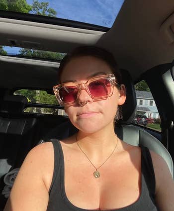 Woman in car wearing sunglasses and a tank top, sunlight on face