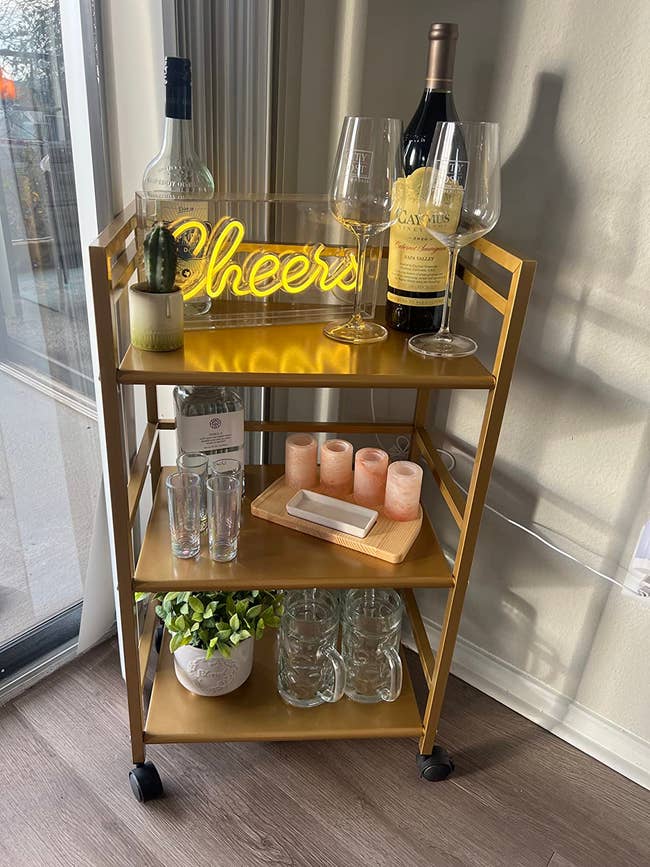 reviewer's three-tier gold cart holding various spirits and glasses