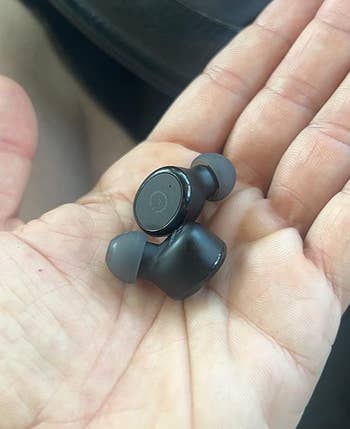 image of black earbuds in the palm of a reviewer's hand