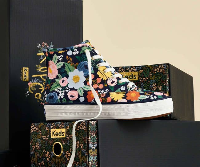 Floral patterned high-top Keds shoe displayed with branded boxes in the background, trendy design