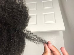 reviewer with 4C hair holding one of their strands