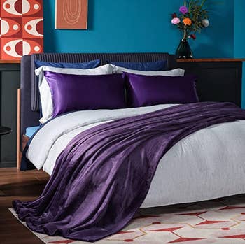 a bed made with the purple satin pillowcases
