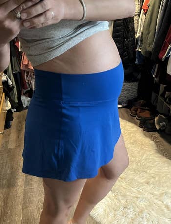 Person successful  a grey  apical  trying connected  a bluish  skirt successful  a closet, showing a broadside  presumption    of the outfit