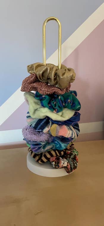 Several scrunchies successful  assorted  textures and patterns stacked connected  a golden  holder