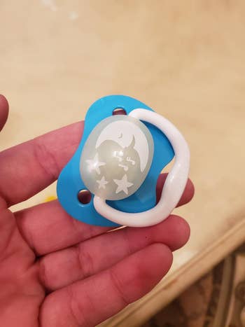 A reviewer holding the pacifier in blue