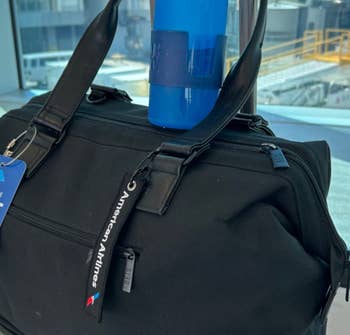 another reviewer's fully expanded blue water bottle on a suitcase