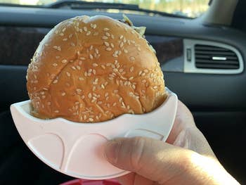 reviewer holding the white half moon-shaped holder with a burger in it