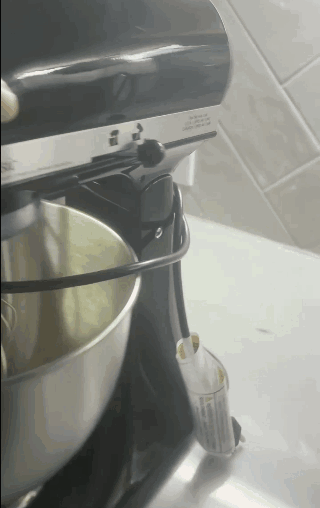 Stand mixer blending dough in a stainless steel bowl on a countertop