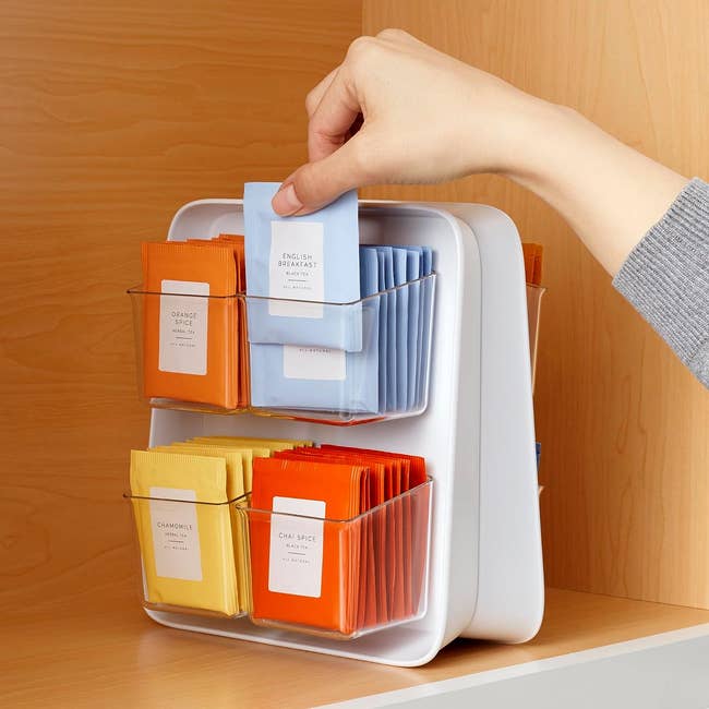 model grabbing a tea from double-sided organizer filled with tea bags