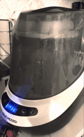 Baby Brezza appliance with digital display in a kitchen, used for making baby formula