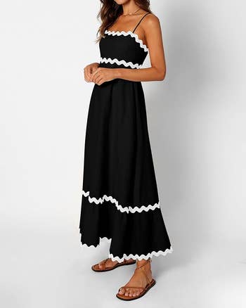 model  in a sleeveless, spaghetti strap black maxi dress with white zigzag trim 