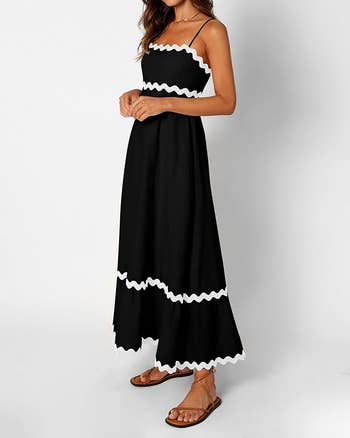 model  in a sleeveless, spaghetti strap black maxi dress with white zigzag trim