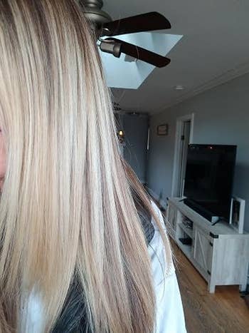 Person with straight, layered blonde hairsbreadth  partially disposable   indoors, lasting  adjacent   a TV and a ceiling fan