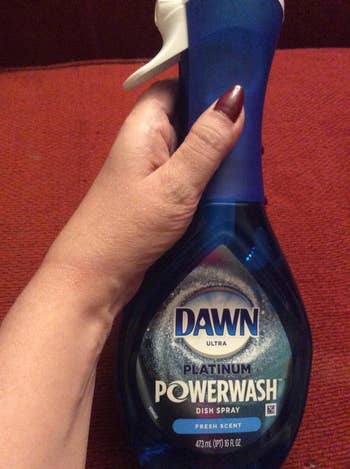 reviewer holding the blue bottle of dawn dish spray