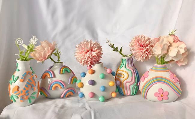 White vase with tigers and leaves decorated, white vase with rainbows all around, white vase with 3D polka dots, white vase with retro pastel lines, white vase with pink flowers decorating it and pastel swirls