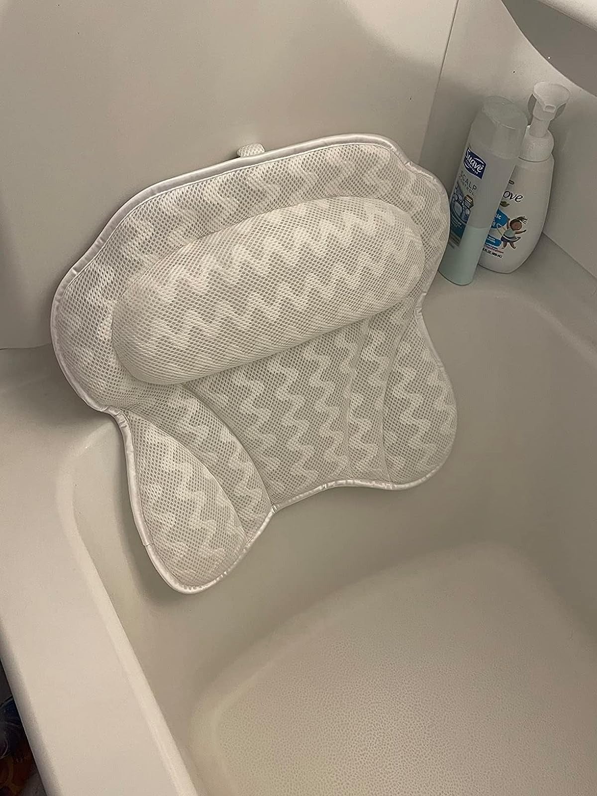 reviewer showing the tub pillow that is attached to the wall with suction cups