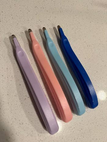 Four tweezers with ergonomic handles successful  assorted  shades are displayed connected  a countertop, highlighting their plan  and assortment  for shopper interest