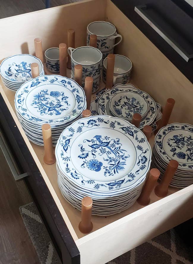 a porcelain dish set organized in a drawer using the peg board inserts