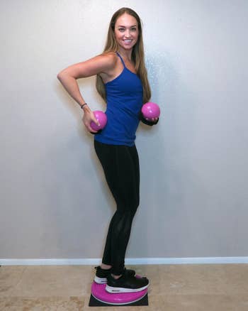 reviewer standing on the pink twist board and holding pink weighted balls