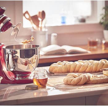 the red stand mixer with its head tilted and fitted with the dough hook attachment next to some shaped dough loaves