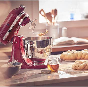 the red stand mixer with its head tilted and fitted with the dough hook attachment next to some shaped dough loaves