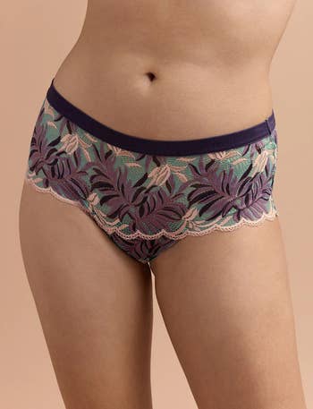 model showing the front of the cheeky underwear in blue with purple palm print all over