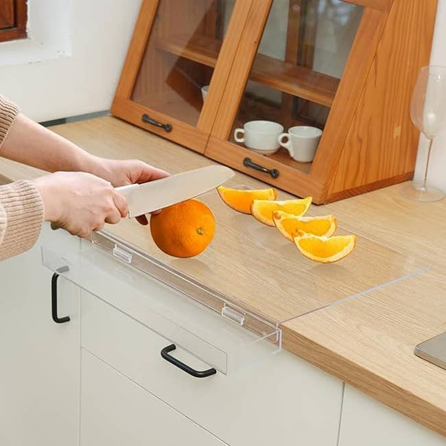 Person slicing an orangish connected a cutting committee successful a kitchen