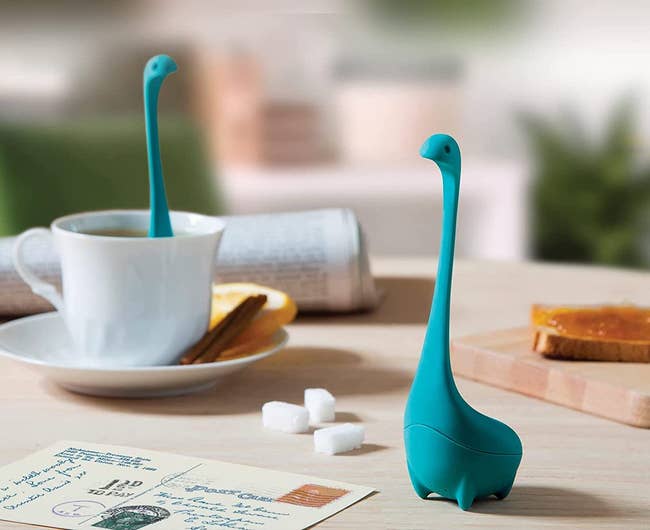 the turquoise Nessie tea infuser on a table and one in a teacup