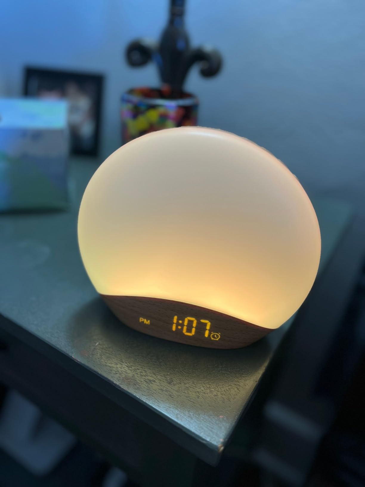 Round sunrise alarm clock glowing softly and displaying the time 1:07