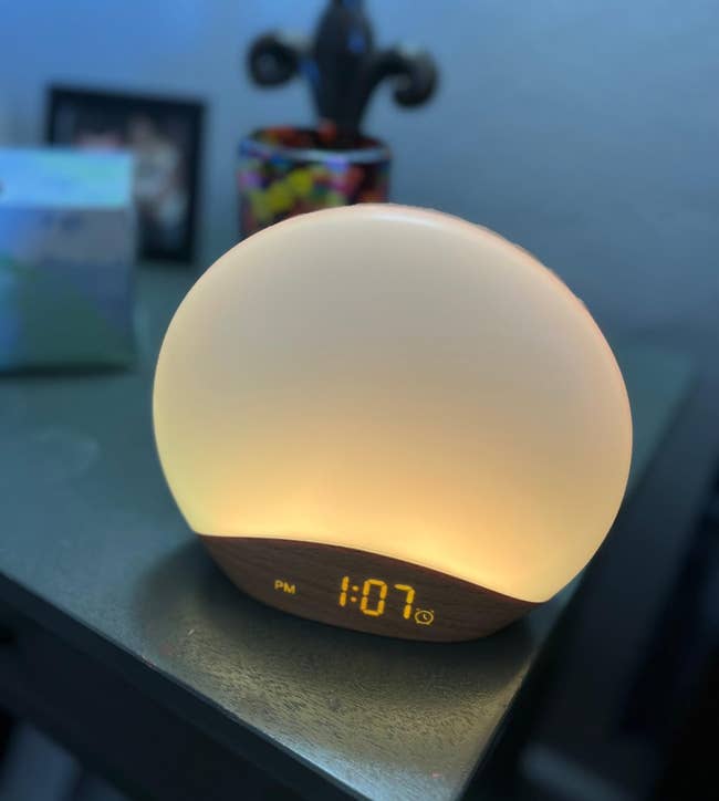 Round sunrise alarm clock glowing softly and displaying the time 1:07