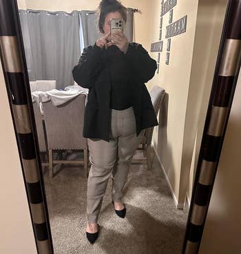 Person in a mirror selfie wearing a black blazer, plaid trousers, and black heels. Shopping for a business-casual outfit