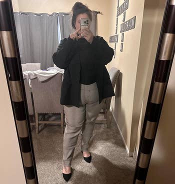 Person in a mirror selfie wearing a black blazer, plaid trousers, and black heels. Shopping for a business-casual outfit