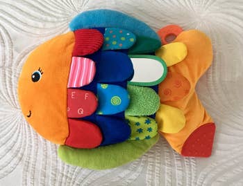 Stuffed fish toy with various textures and patterns, featuring alphabet and shapes for tactile learning