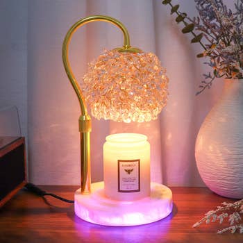 Elegant decorative lamp with a crystal-inspired shade next to a lit luxury soy candle on a wooden table, creating a cozy ambiance