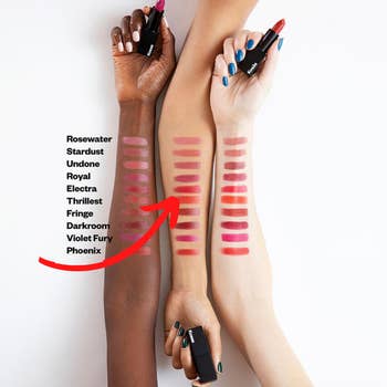Three models of different skin tones with various lipstick swatches on their forearms