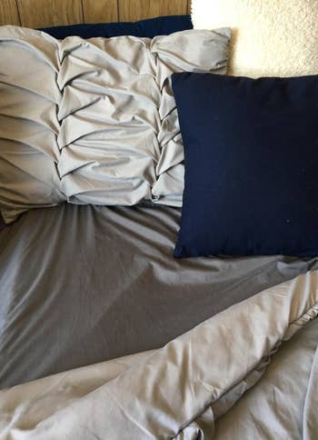 Assorted throw pillows on a bed with gray sheets 