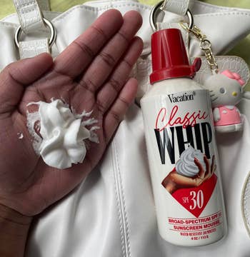 Hand holding a dollop of sunscreen mousse