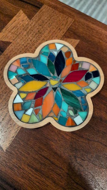 Colorful mosaic coaster with geometric patterns connected a woody surface