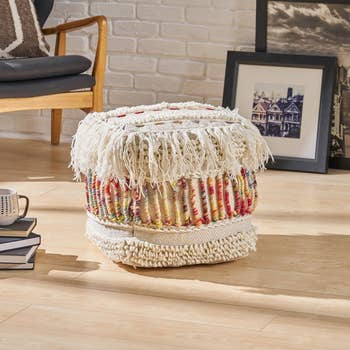 A bohemian-style ottoman with fringes and colorful woven patterns