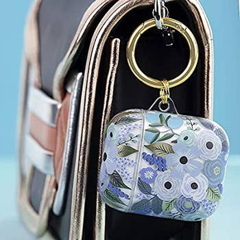 airpods case with blue flowers and gold ring hooked to a purse
