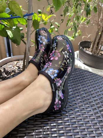 model wearing black garden shoes with blue and pink flowers on them