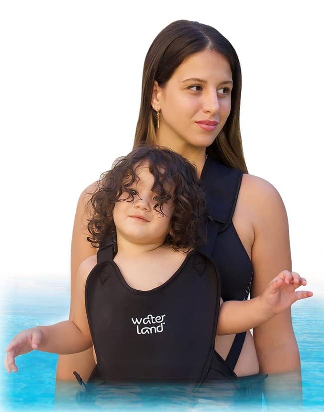 model wearing the black waterproof baby carrier with a toddler strapped in