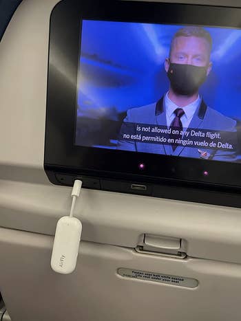 Reviewer's AirFly Pro plugged into the tv screen on a plane