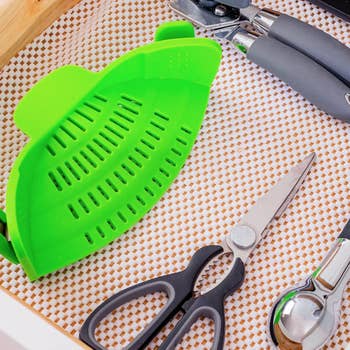 the space-saving green silicone strainer stored in a drawer