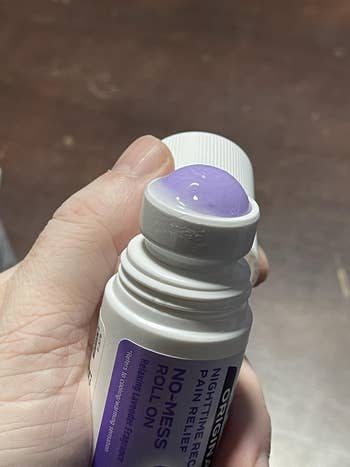 Person holding a no-mess roll-on symptom alleviation applicator, dispensing a gel