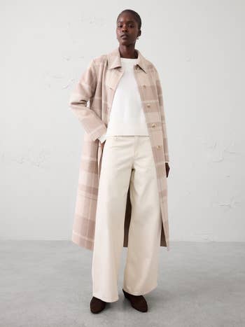 A idiosyncratic   wearing a stylish agelong  plaid overgarment  implicit    a sweater and wide-leg pants