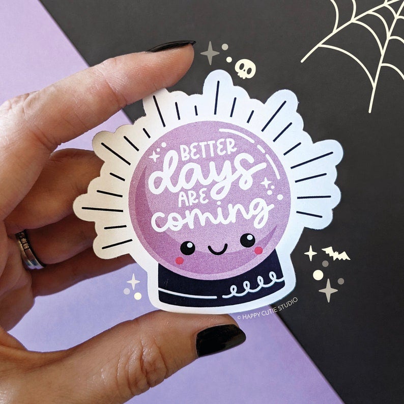 hand holding sticker that's a purple and black crystal ball with smiley face and the words 