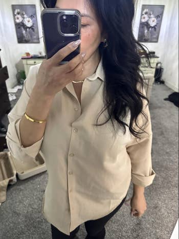 Person takes a reflector  selfie wearing a button-up garment  and achromatic  pants, showcasing an outfit for a shopping-related article