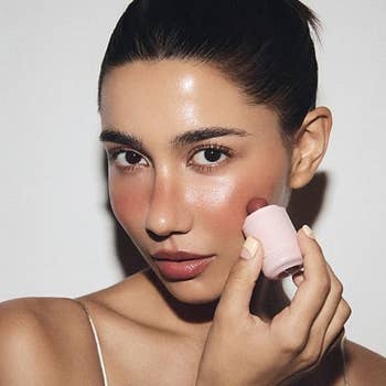 Person applying blush instrumentality to cheek, showcasing a quality merchandise successful a buying article